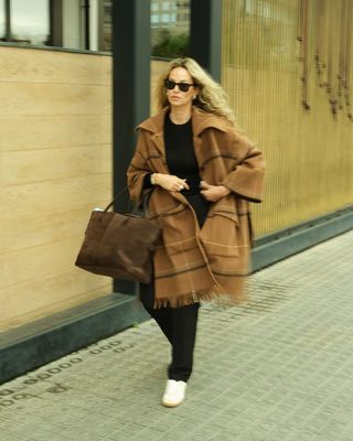 @anoukyve wearing blanket coat with black top and jeans