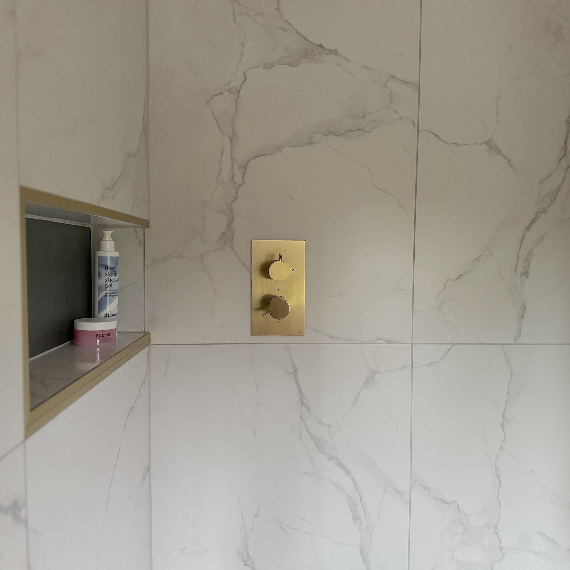 close up of porcelain tiles with brass shower controls