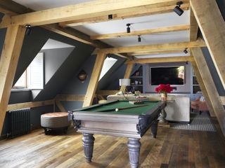 small media room with pool table, beams, wooden floor, couch and armchair