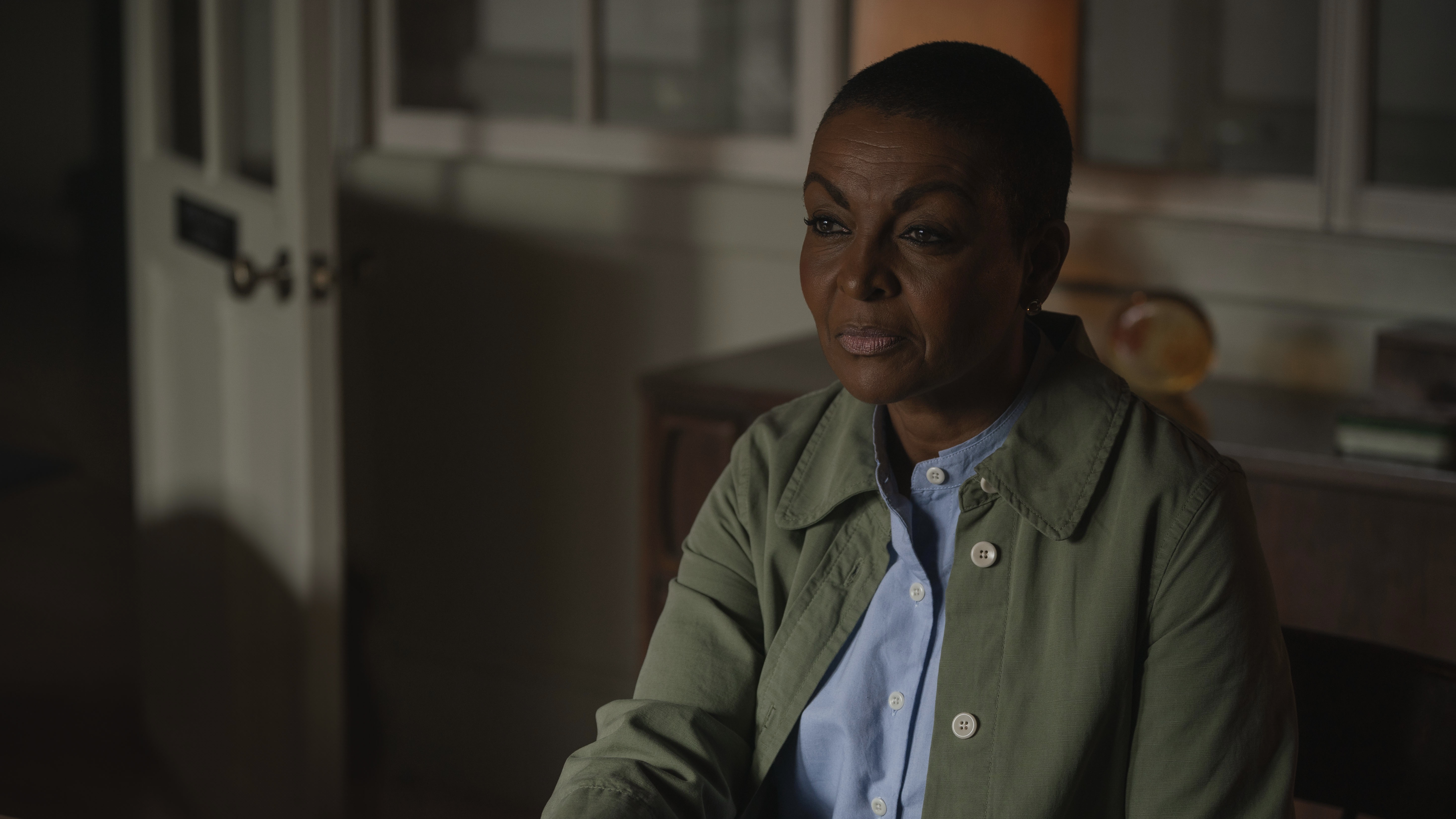 Adjoa Andoh in a green jacket and seated as Lady Heather Nancarrow in The Red King.