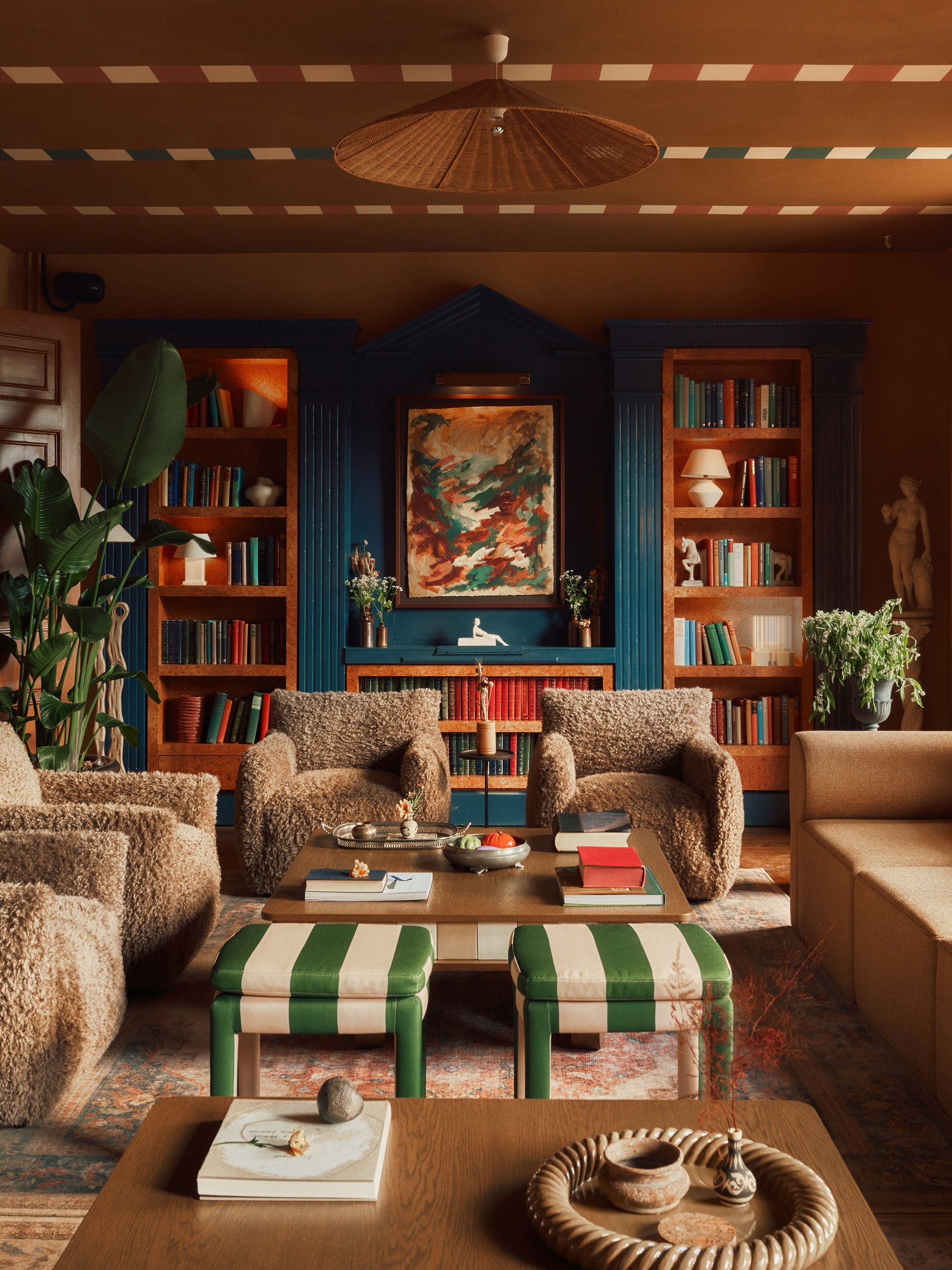a golden painted room with stripes across the ceiling, striped stools and comfortable looking chairs