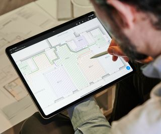 man looking at tablet screen with underfloor heating diagram