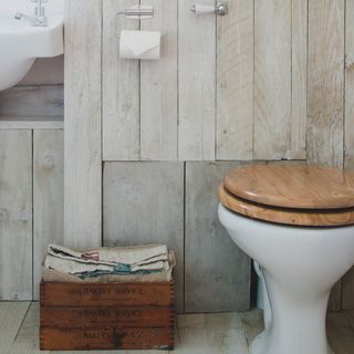 bathroom with wooden wall and commode with toilet paper