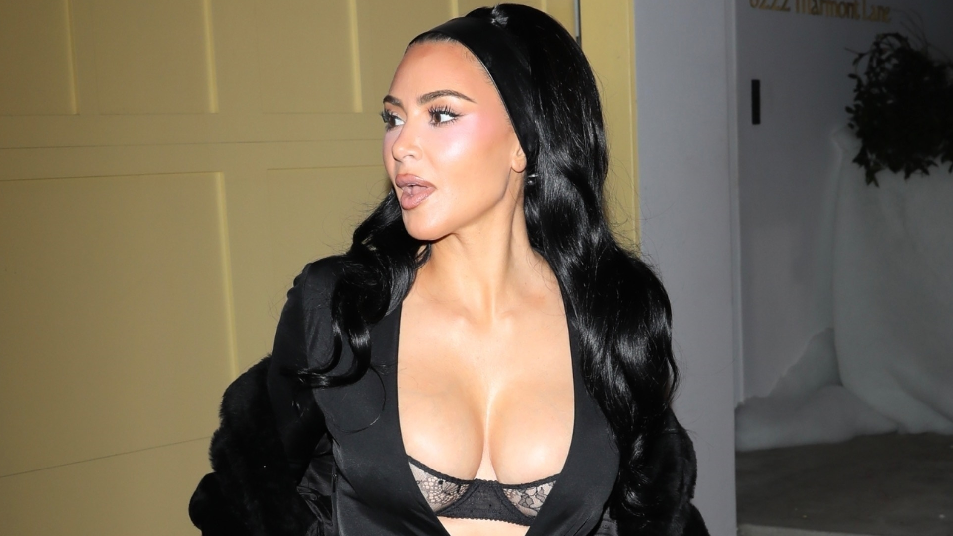 Kim Kardashian attended a holiday party wearing a peekaboo bra, a plunging maxi dress, and a matching fur