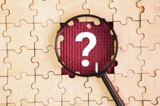 Magnifying glass and wooden puzzle with a question mark in the middle
