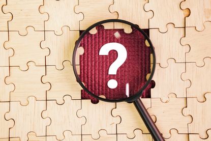 Magnifying glass and wooden puzzle with a question mark in the middle