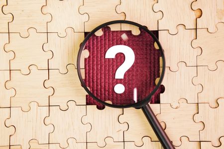 Magnifying glass and wooden puzzle with a question mark in the middle
