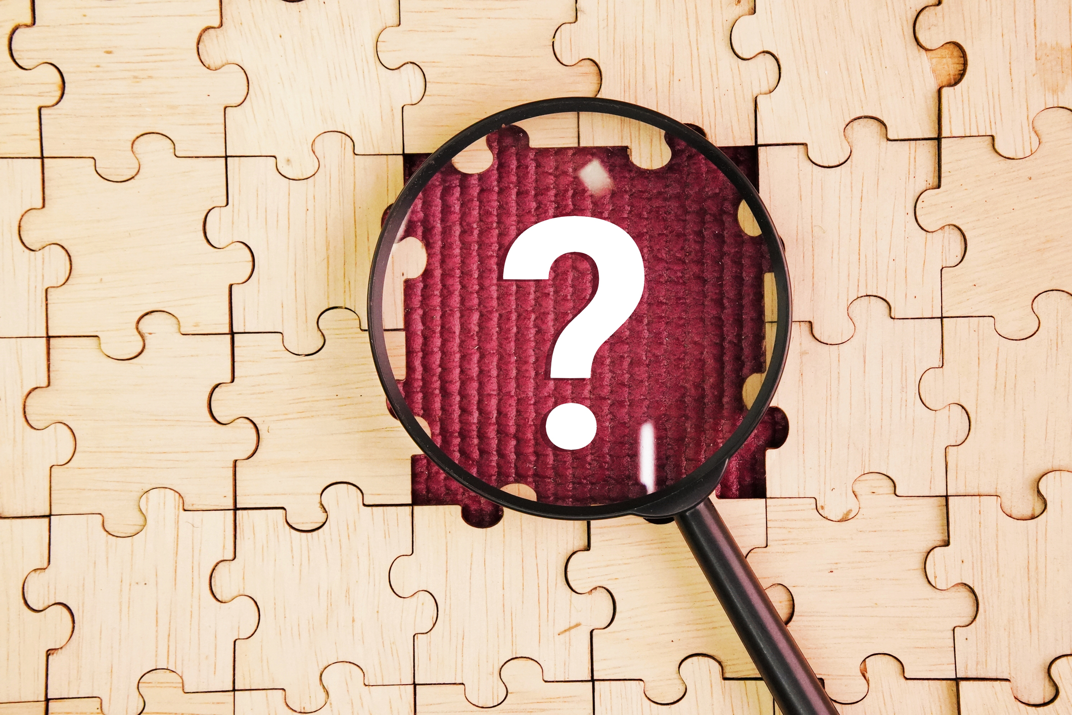 Magnifying glass and wooden puzzle with a question mark in the middle