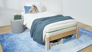 The Helix Kids Mattress placed on a light wooden bed frame and dressed with a blue bed throw and a cuddly sloth toy