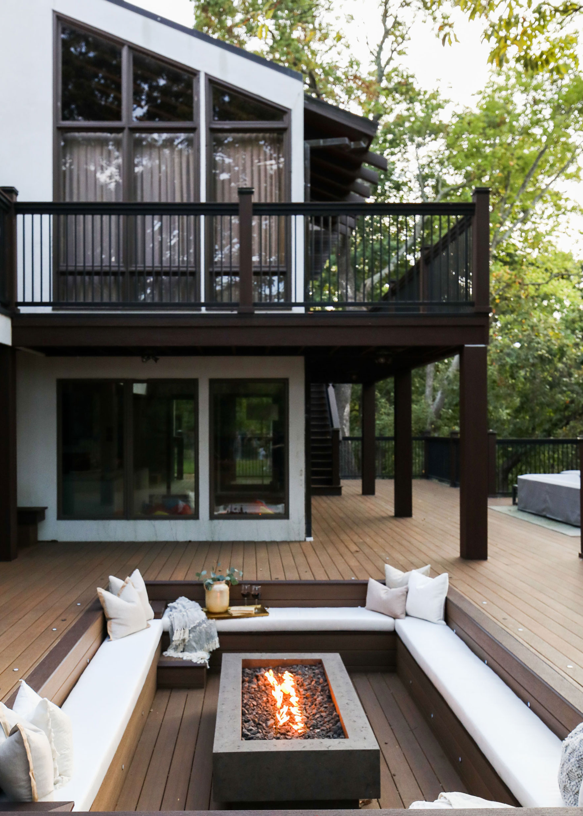 a conversation pit in a backyard deck with a firepit in the middle