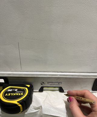 hand drawing plumb line on white wall with spirit level