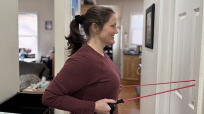 Woman exercising with resistance band attached to door at home