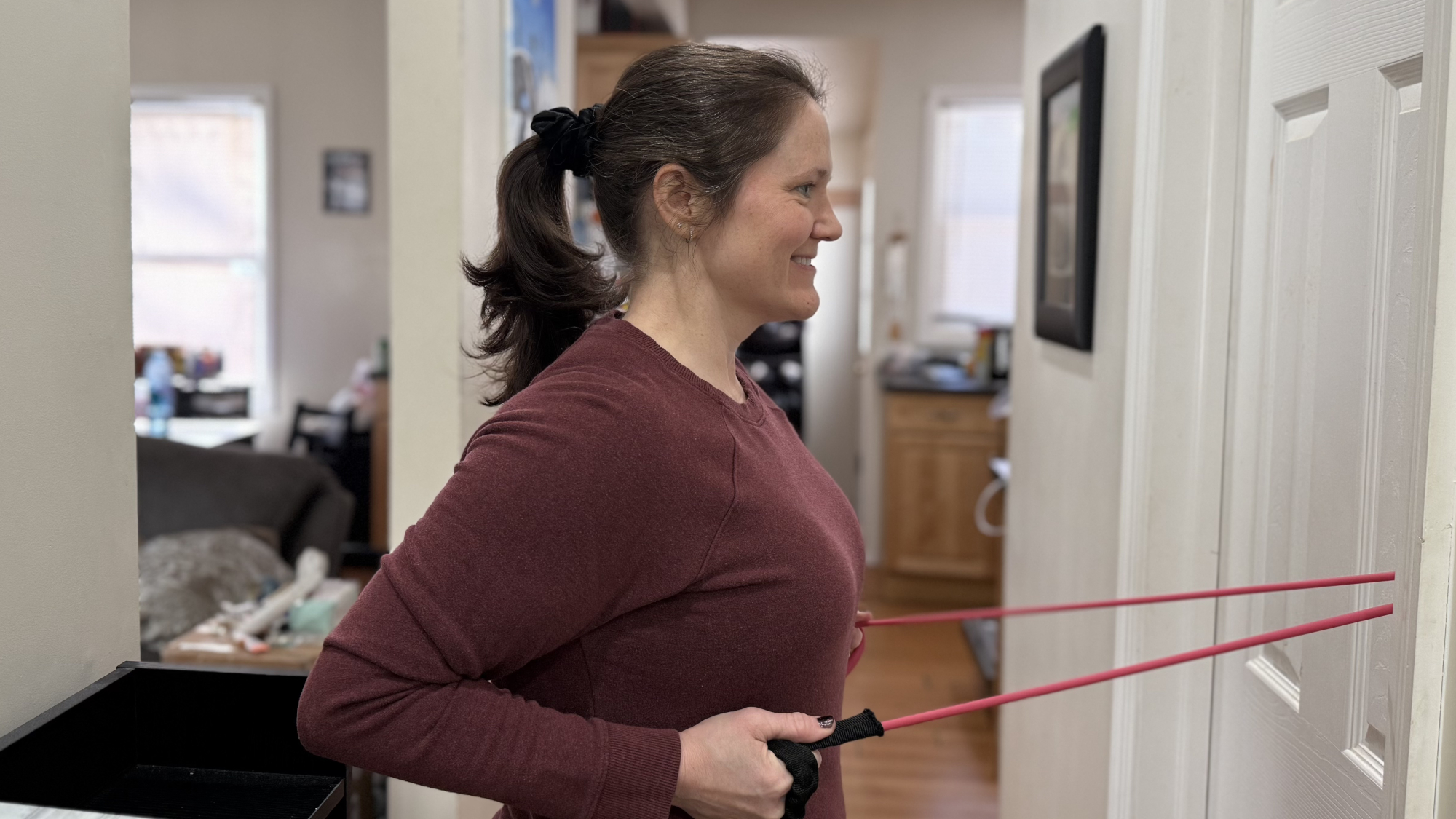 Woman exercising with resistance band attached to door at home