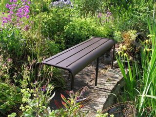 metal bench surrounded by flower beds
