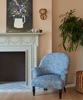 living area with blue armchair and marble fireplace and pale pink walls