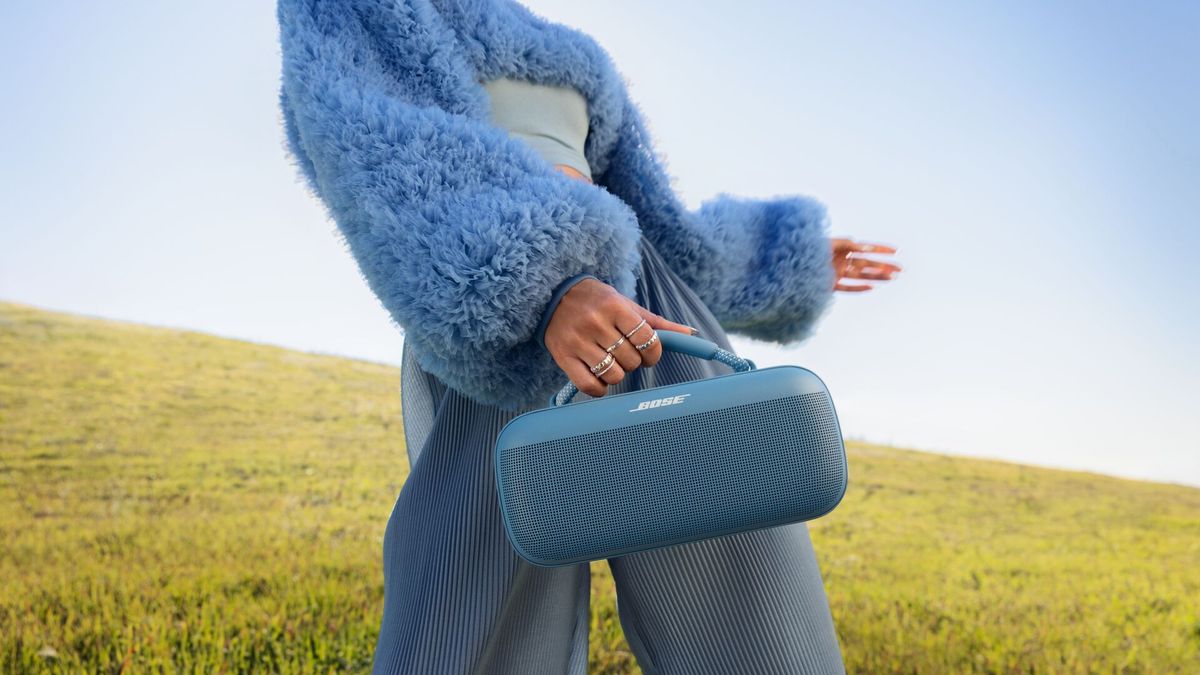 Woman in a field holding a Bose SoundLink Max 