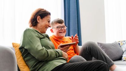 Boy with down syndrome enjoy spending time with mother and watching mobile phone