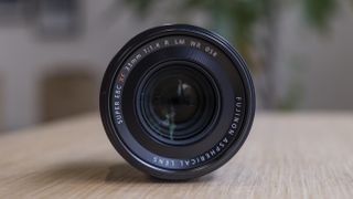 The Fujifilm XF33mm f/1.4 lens on a wooden table