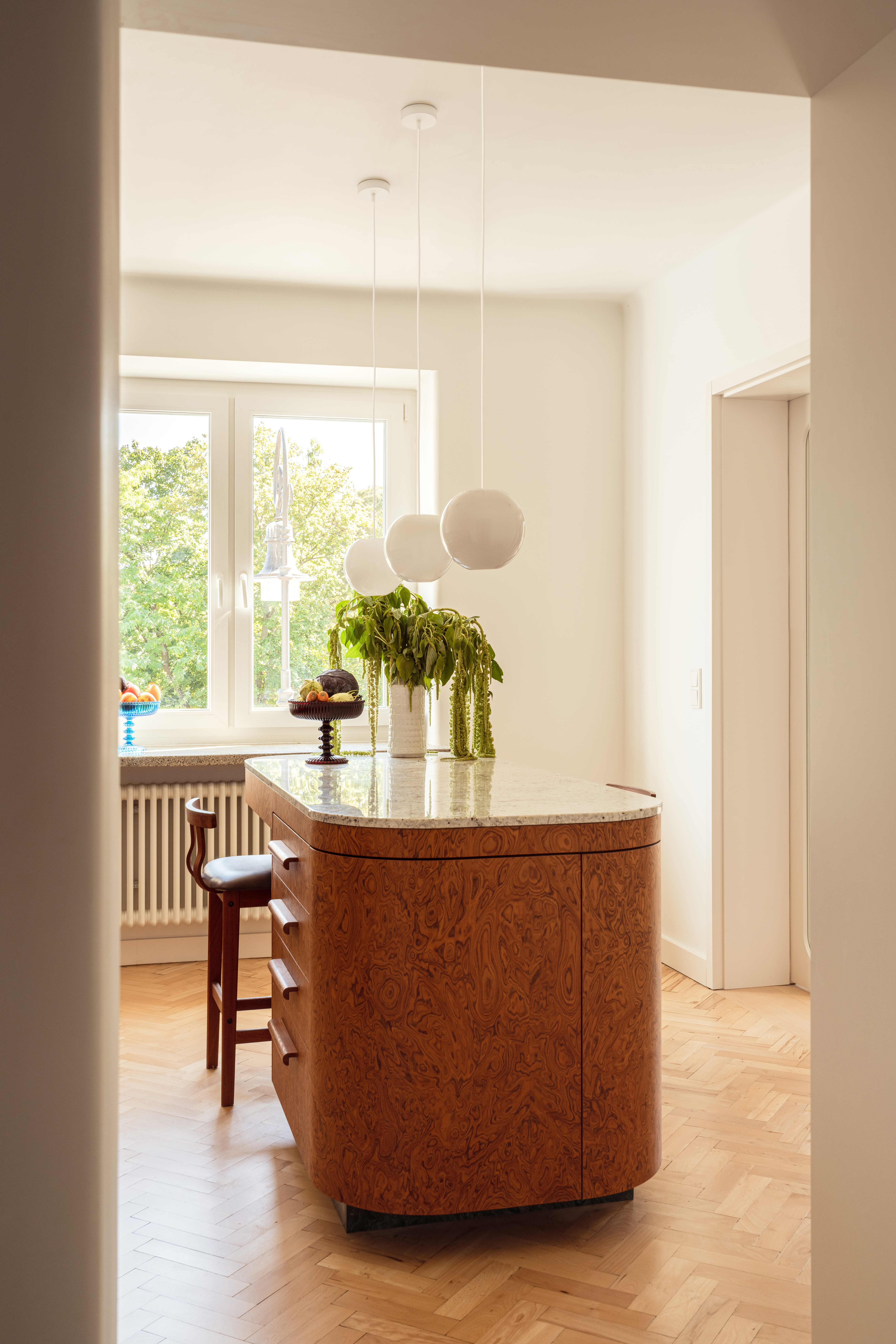 bright and beautiful kitchen with a burl wood island and white pendant lights