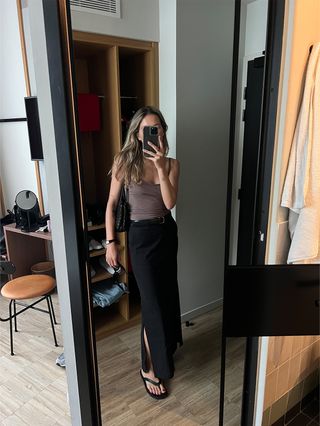 Eliza Huber wearing a J.Crew x Maryam Nassir Zadeh camisole in taupe with a black tailored COS maxi skirt and flip flops.