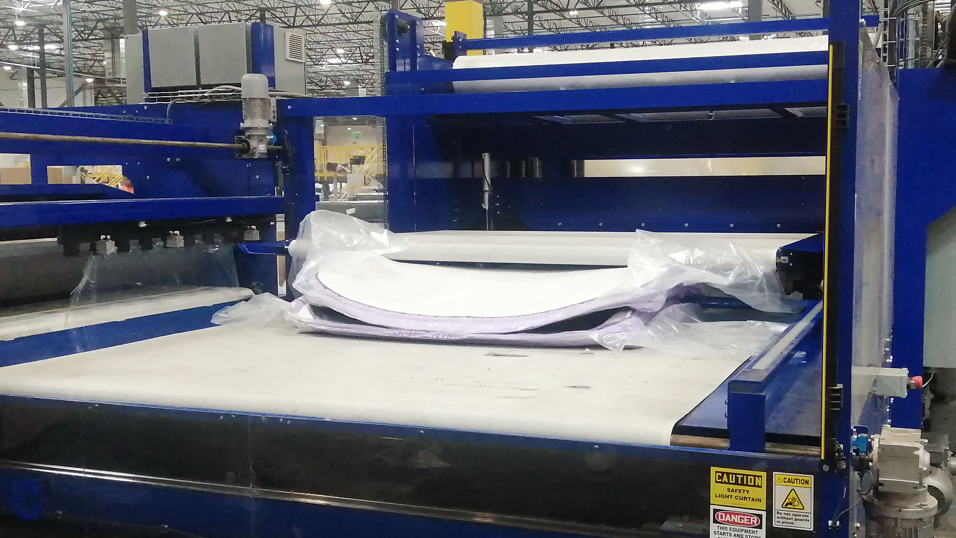 Mattress in a box being compressed by machine in 3Z Brands mattress factory