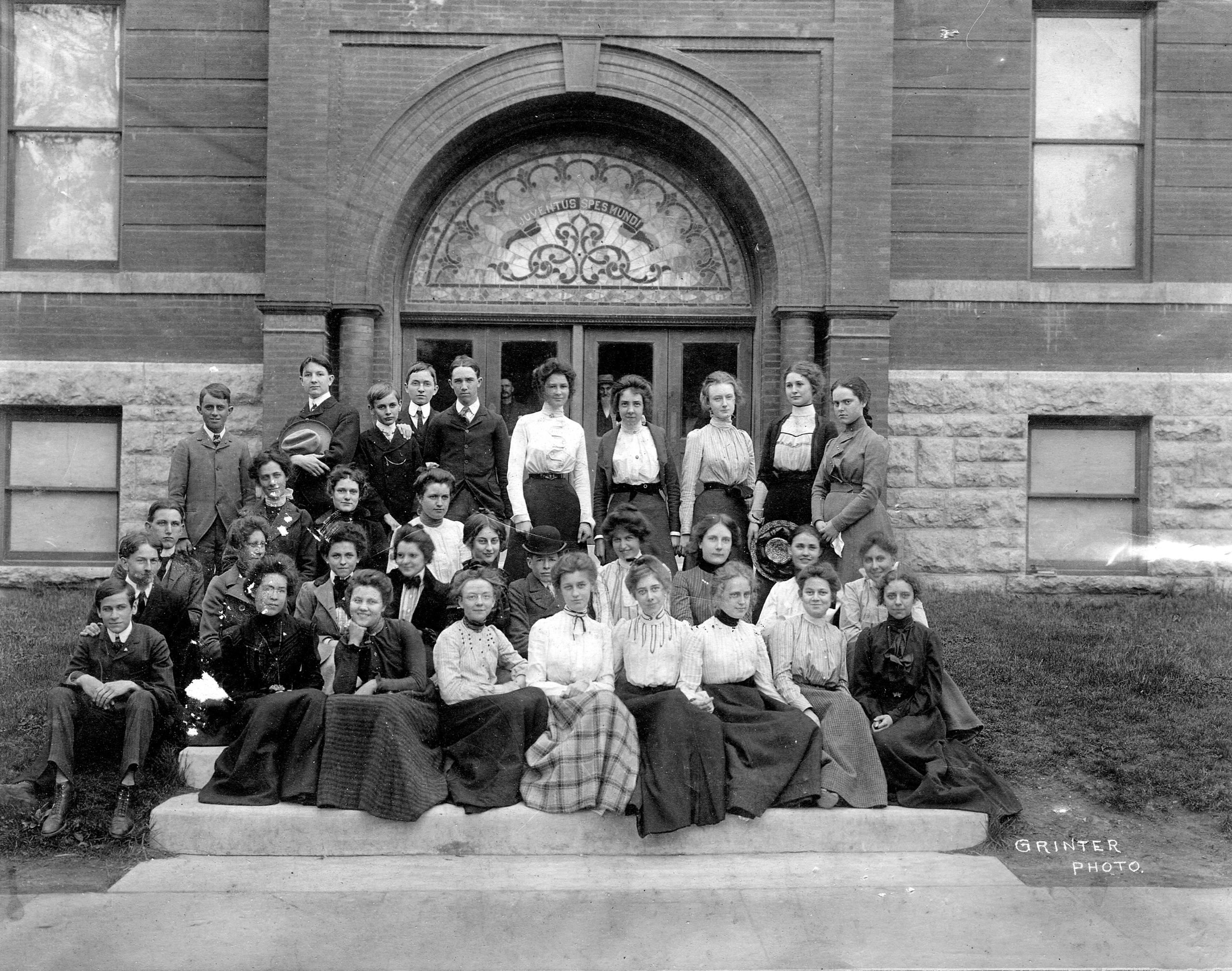 About 35 smartly dressed teenagers pose on the stone steps of an arched school entrance with a stained-glass window reading &amp;ldquo;Juventus Spes Mundi&amp;rdquo;