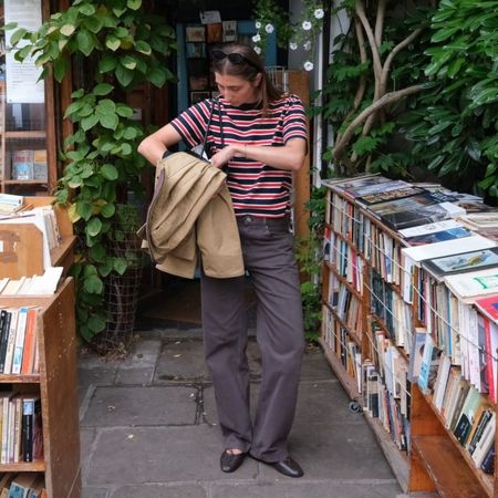Influencer @poppyalmond wears brown jeans with brown leather ballet flats and a striped t-shirt.