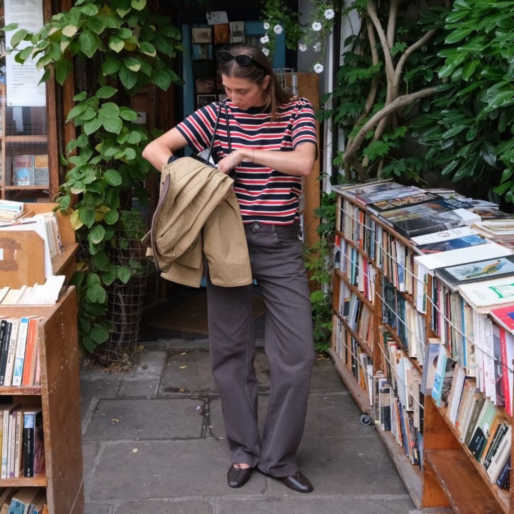 Influencer @poppyalmond wears brown jeans with brown leather ballet flats and a striped t-shirt.