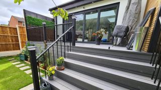 A grey raised deck with steps on back of house