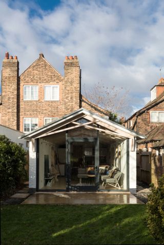 Single storey kitchen extension at the back of a house, leading onto a garden, with a large sofa and seating inside