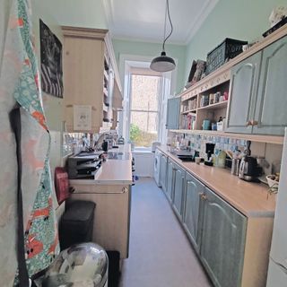 Shot of a narrow light green kitchen with light grey floors