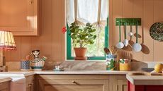 a pink kitchen with colorful decor and utensils stored in jars and on the walls