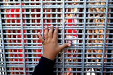 A child reaching for a San Diego border fence.