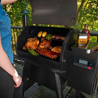 large barbecue with open lid filled with meat, chicken, ribs