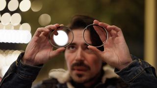 A man holding two filters to demonstrate the minimal reflection characteristic of the NiSi Pro Nano Air UV filter