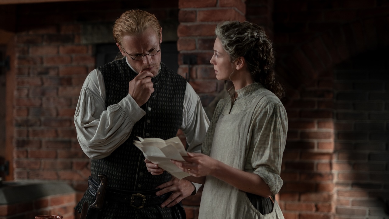 Claire showing Jamie a piece of paper in Outlander Season 8
