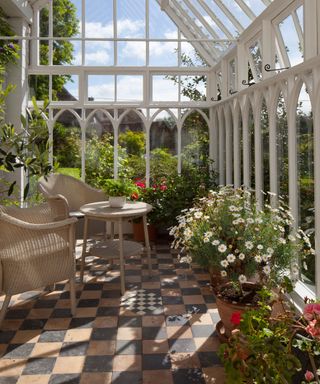 Interior of old style English wooden conservatory with wicker seating and flower pots