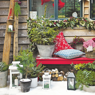 Christmas decorations, an outdoor bench with light snow cover, cushions, Christmas tree baubles and stars. Candle lanterns.