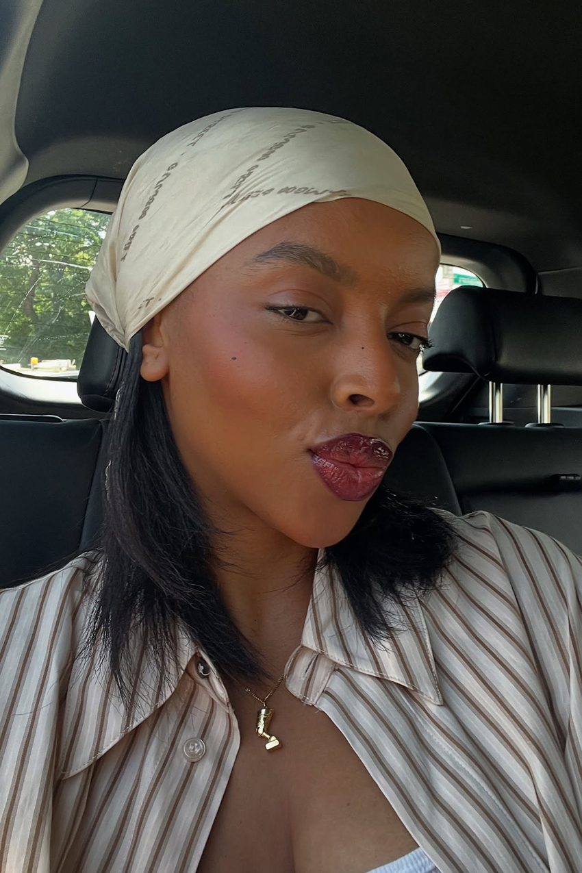 a woman wearing a cream silk scarf and striped button down