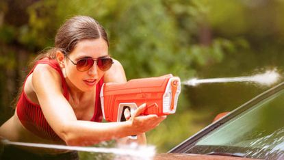 SPYRA water gun in red colorway being used by a woman to shoot water
