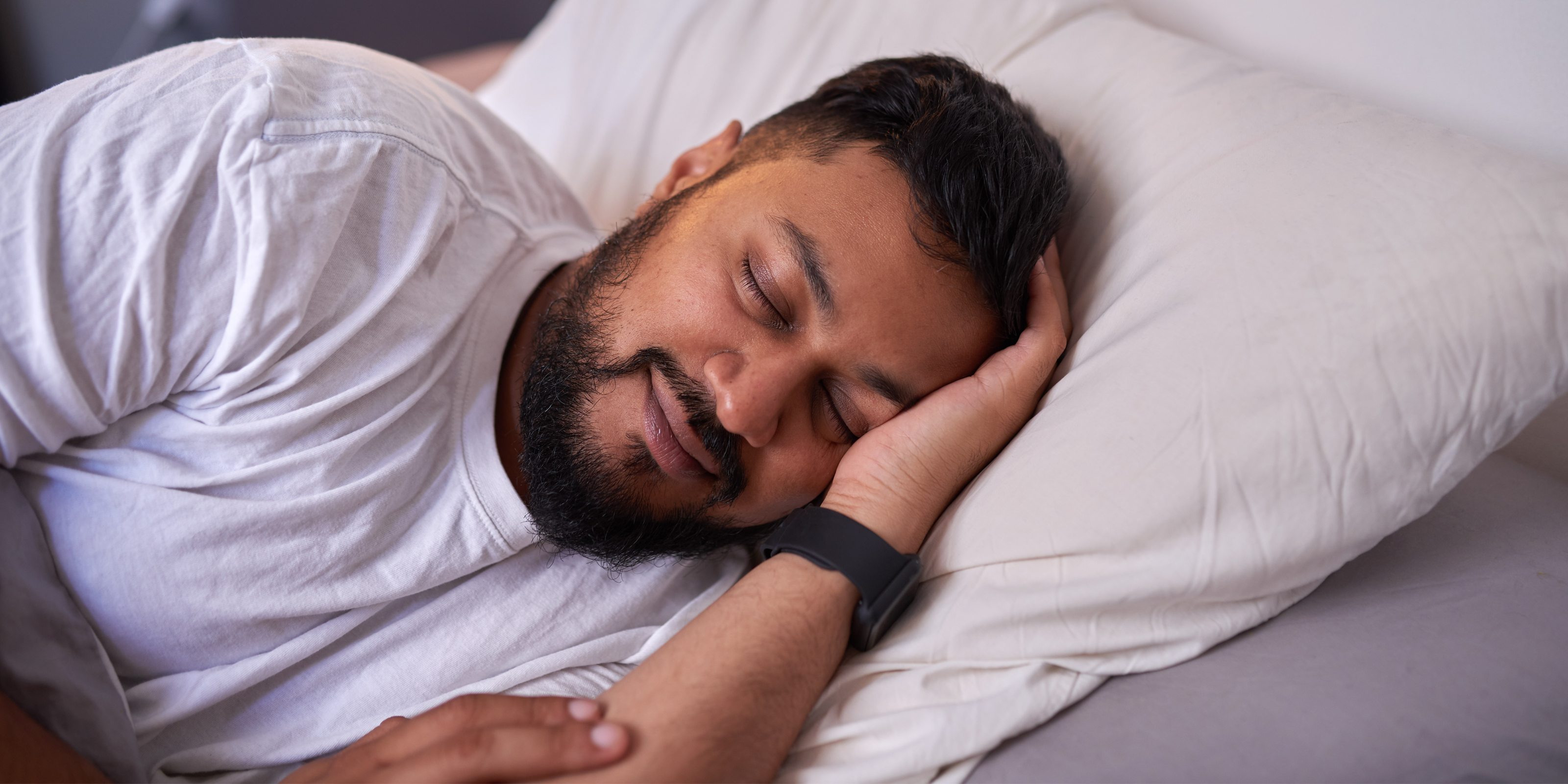 Image of a man sleeping while using a fitness/sleep tracker