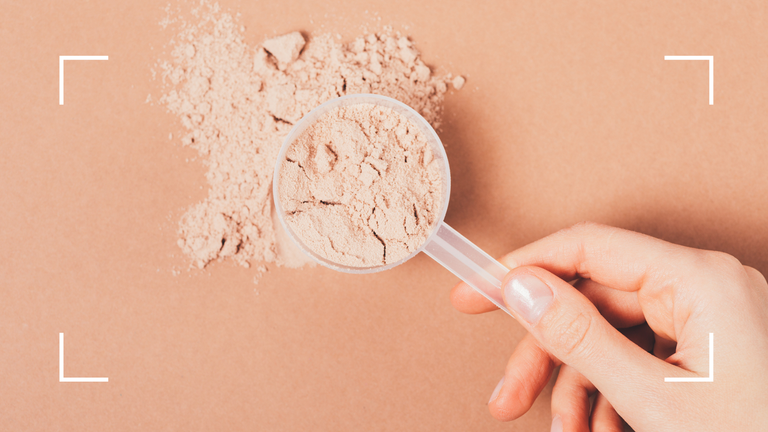 Woman's hand holding a scoop of protein powder