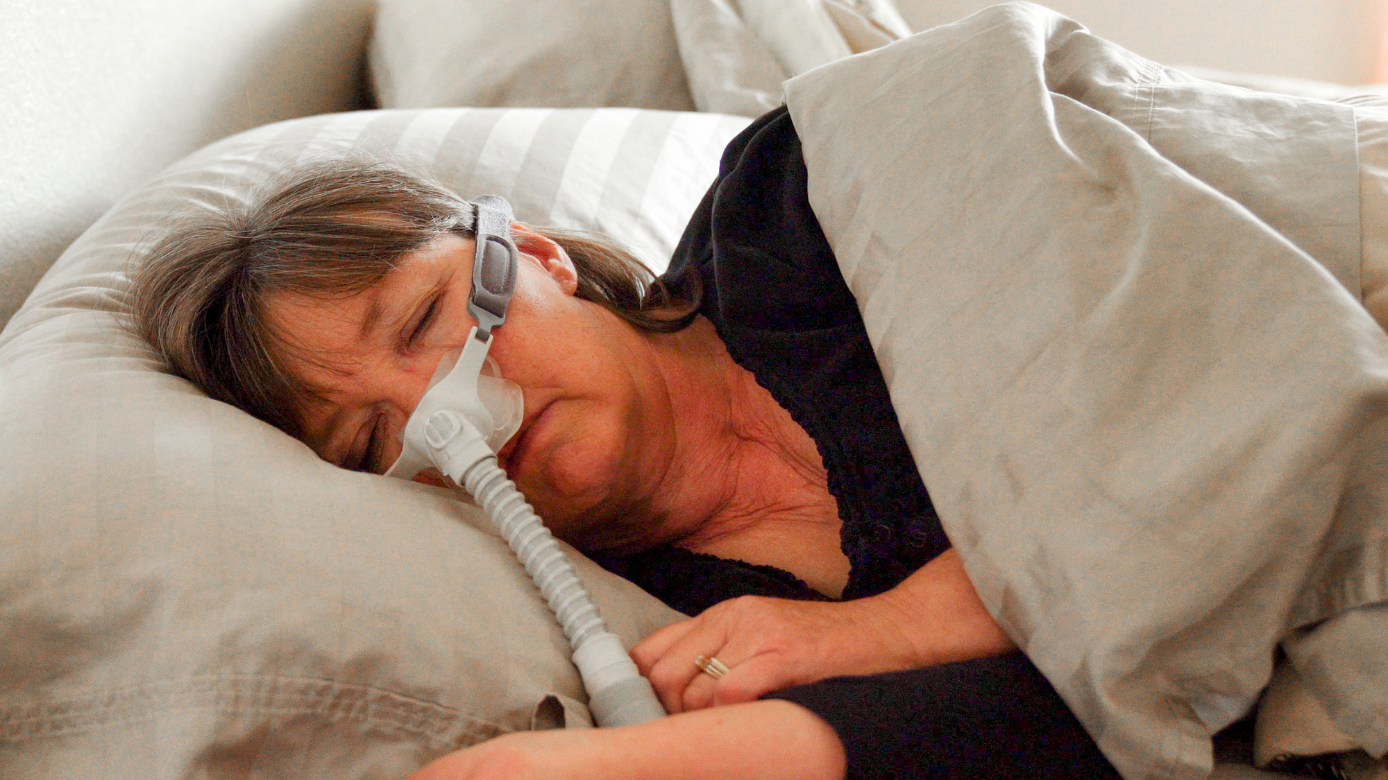 A woman wears a cpap machine while sleeping on her side to stop snoring