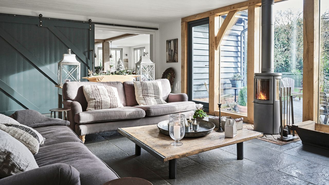 Rustic-style living room with wooden beams and a dark grey sliding door to divide the open plan space