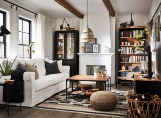 A modern traditional living room with black cabinetry, built-in bookshelves, jute poof and wooden coffee table