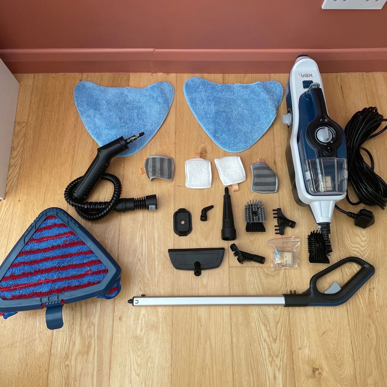 VAX Total Home Steam Cleaner components laid out on wood-effect flooring