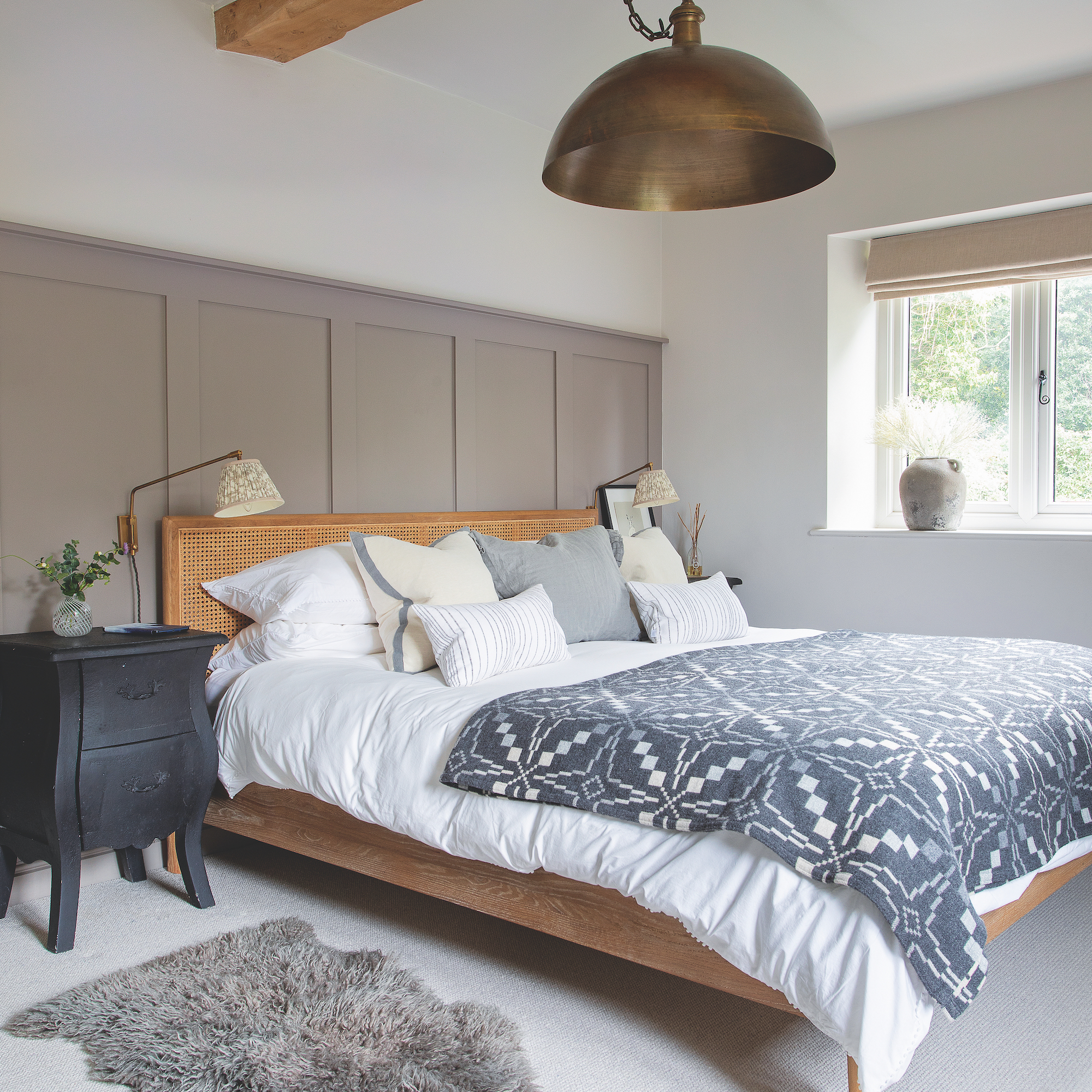 bedroom with taupe painted panelling behidn bed and angled wall lights