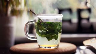 Steaming up of fresh mint tea sitting next to open window, one of the detox drinks to lose weight