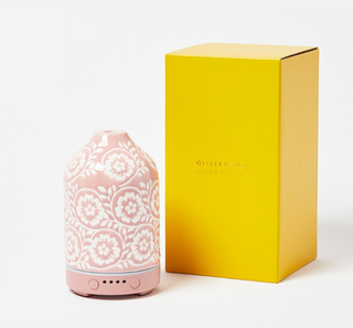 A pink essential oil diffuser next to a yellow box on a white background.