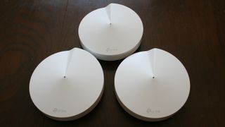 Tre stycken vita TP-Link Deco M5 ligger mot en svart bakgrund